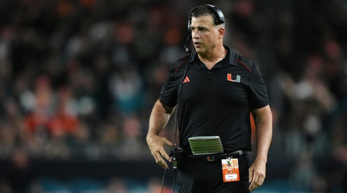 Mario Cristobal walks along the sideline with a hand on his waist